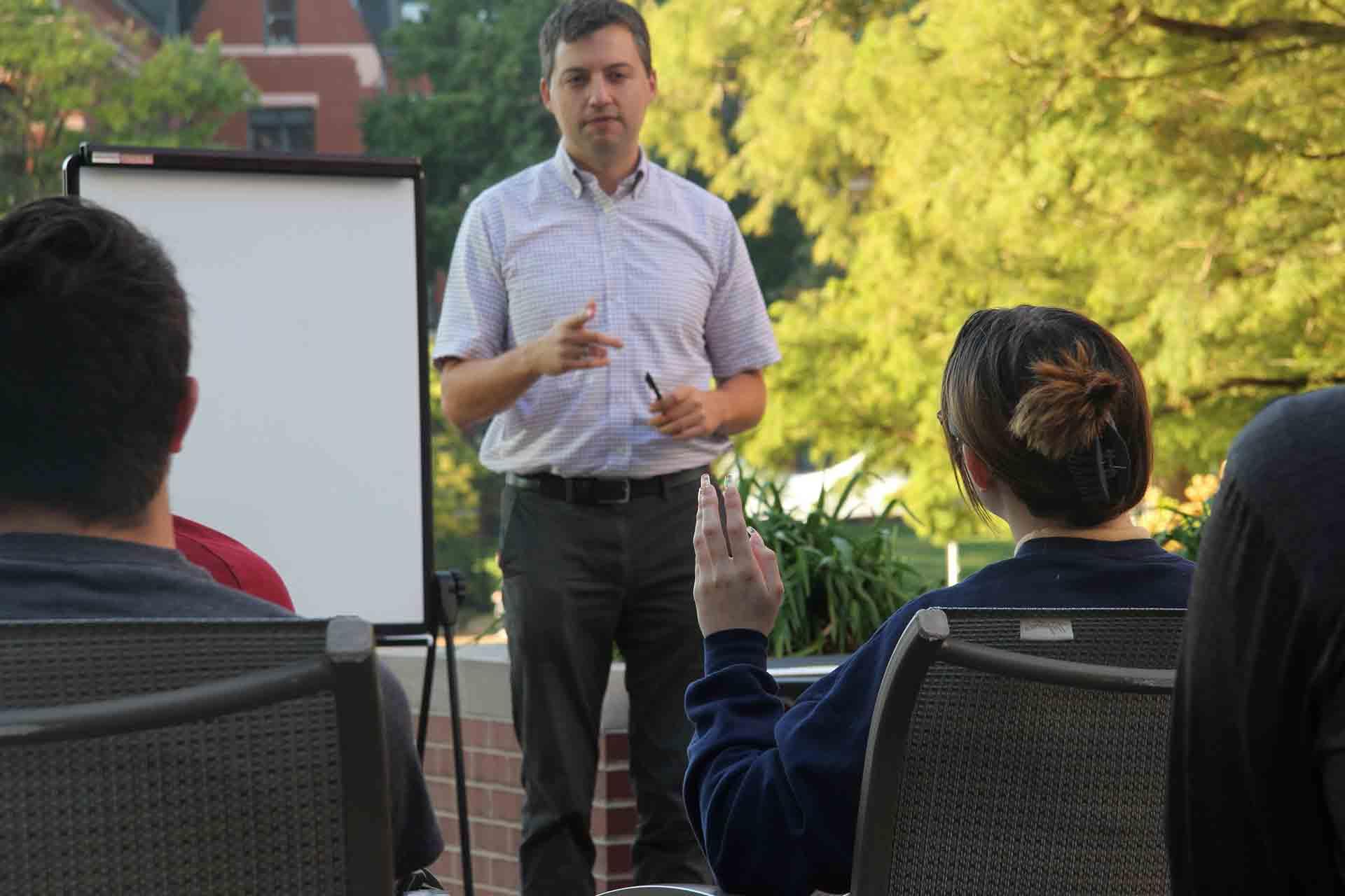 A 博彩网址大全 professor addresses student questions during an outdoor class session.