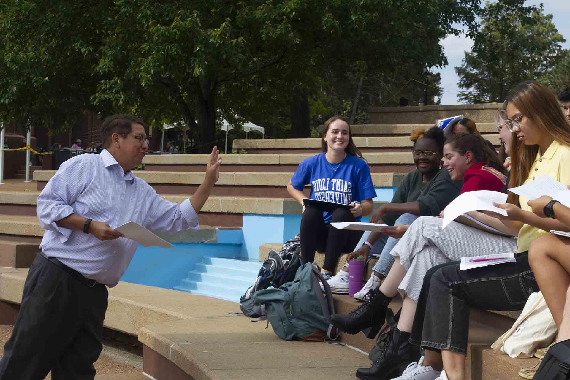 A professor leads a discussion while students sit near one of 博彩网址大全's many fountains.