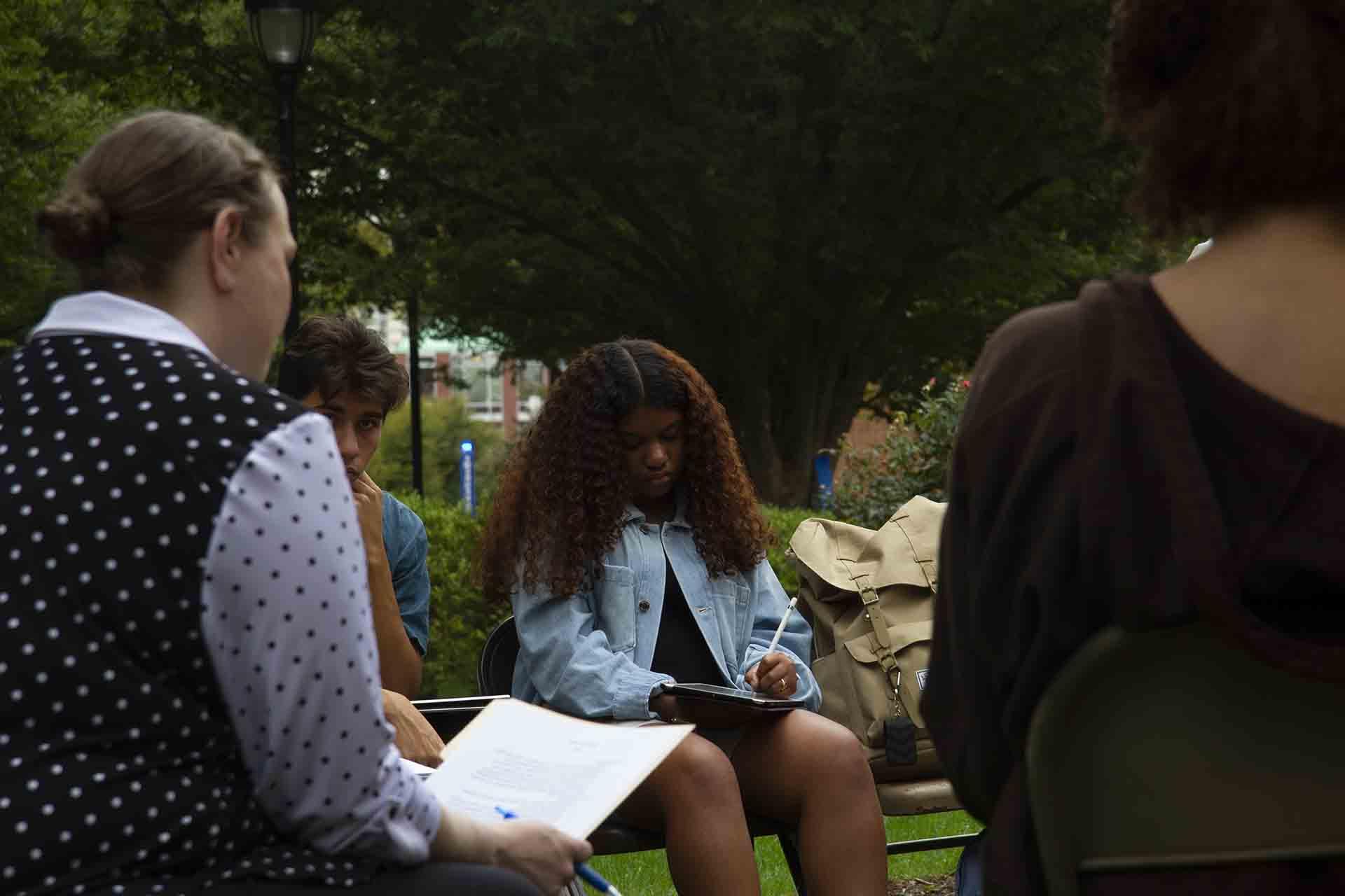 Students take notes during an outdoor class session.