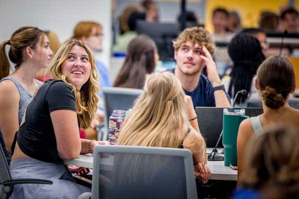 A group of students sits around a table in class settting